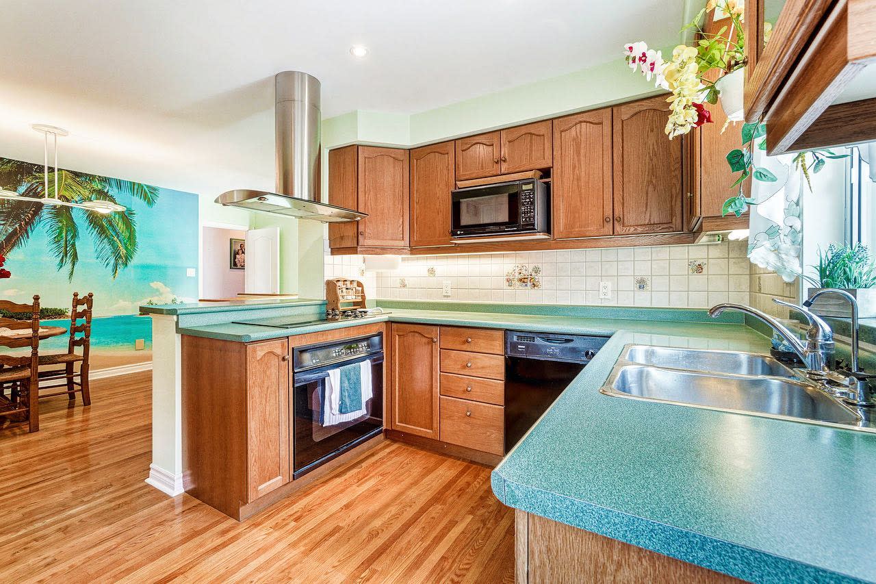 Tropical-style kitchen with wood cabinets, green countertops, and beach mural dining area.